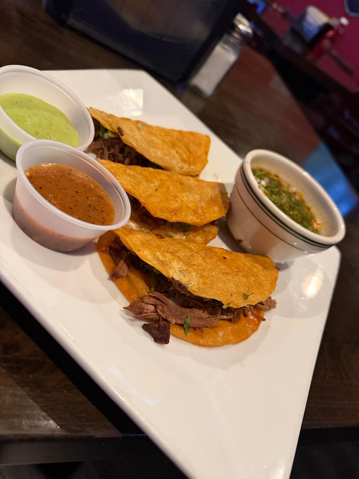 Birria tacos with red and green salsa on white plate at Westrail